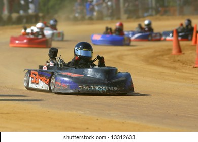Karts racing on a dirt track.