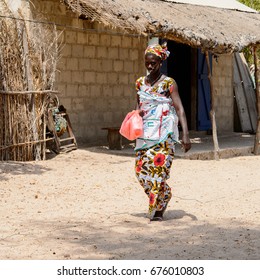 KASCHOUANE, SENEGAL - APR 29, 2017: Unidentified Diola woman walks along the street in Kaschouane village. Diolas are the ethnic group predominate in the region of Casamance - Shutterstock ID 676010803