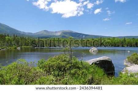 Katahdin mountain range in Baxter State Park, Maine, rises behind a serene pond on a beautiful summer day