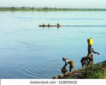 Katanga, DRC, 11th June 2006: Women fetching water from river Congo with men in a canoe in the background