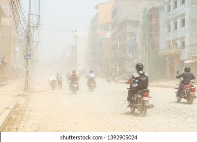 KATHMANDU, NEPAL - 9. MAI 2019: Verkehr auf Boudha Road legte Staub in die Luft, da die Straße nicht erpresst wird. Es steht für die Bewohner des Gebiets auf dem Spiel.