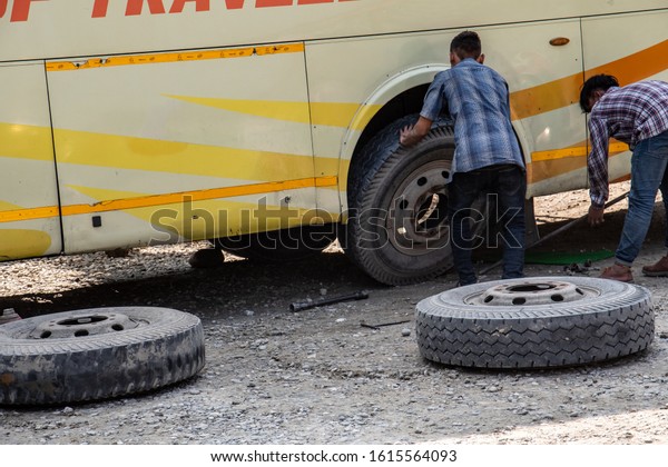 KATHMANDU,\
NEPAL - NOV 6, 2019: two young men replace a flat tire on a bus on\
the way to Kathmandu, Nepal, on Nov 6,\
2019.