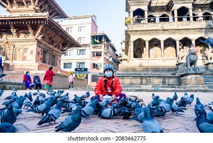 KATHMANDU, NEPAL - October 30, 2021: child wearing mask and selling bird's food during covid pandemic in Patan durbar square at Kathmandu.