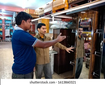 Katni, INDIA - January 2020: Asian Furniture Shopkeeper Presenting Wooden Mirror Almira To The Customer At Showroom 