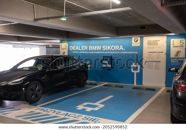 Katowice, Poland\
- September 24, 2021. A static shot of a solid black Tesla Model 3\
dual motor charging at the BMW Sikora AC charging station in a\
sunny autumn day. Selective\
focus.