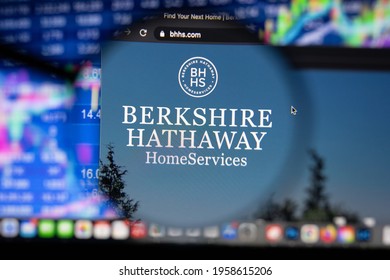 KAUFBEUREN, GERMANY - APRIL 19, 2021: Berkshire Hathaway homeservices logo on a website with blurry stock market developments in the background, seen on a computer screen through a magnifying glass.