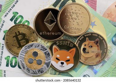 KAUFBEUREN, GERMANY - DECEMBER 04, 2021. Bitcoin, Cardano, Shiba Inu, Ethereum, Ripple, and Dogecoin physical coins laying on top of 100 and 10 Euro bills.