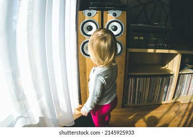 Kaunas, Lithuania; 2022-04-01; Toddler Girl Is Looking Into The Membrane Of Home Sound System Speakers. Vintage Stereo Receiver, Turntable And Vinyl Records Are Seen Next To Her.   