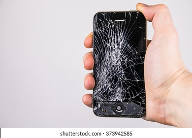 KAUNAS, LITHUANIA - FEBRUARY 8, 2016: Holding broken and screen cracked smartphone.  Broken Iphone 4