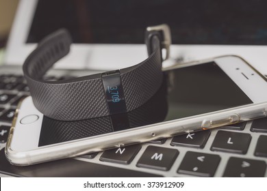 KAUNAS, LITHUANIA - FEBRYARY 06, 2016: Activity tracker (Fitbit Charge HR) placed on MacBook Pro laptop keyboard and iPhone 6S, isolated on black background