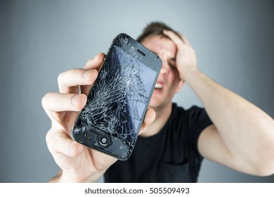 KAUNAS, LITHUANIA - OCTOBER 27, 2016: Sad man holds broken smartphone. Screen broken iphone. Not working phone