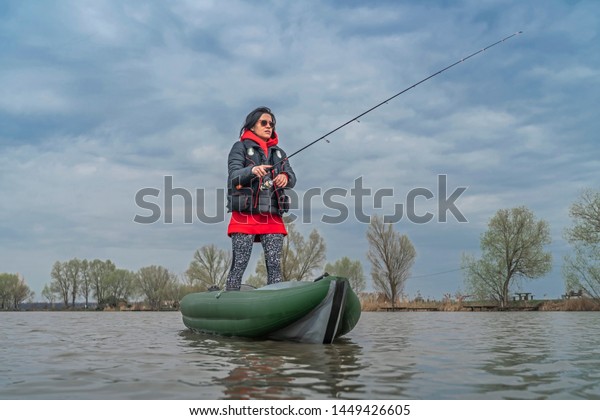 Kayak fishing at lake. Fisherwoman on inflatable\
boat with fishing tackle.