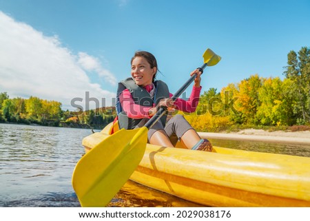 Kayak fun water sports on river in Laurentians, Quebec, Canada. Summer travel destination. Happy Asian woman kayaker kayaking in lake.