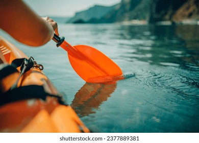 Kayak paddle sea vacation. Person paddles with orange paddle oar on kayak in sea. Leisure active lifestyle recreation activity rest tourism travel - Powered by Shutterstock