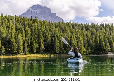 Kayaker explores tranquil waters of Chinook Lake, surrounded by the lush forests and majestic mountains of Alberta, Canada. Experience outdoor adventure and serene nature in this picturesque setting. - Powered by Shutterstock