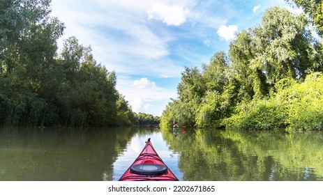 Kayaker Point Of View. Kayak Bow With A View On The River Green Trees And Two Kayakers. River Kayaking Concept. Active Vacations In Wild Nature