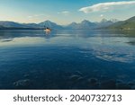 Kayakers paddling on Lake McDonald in Glacier National Park on calm water in the summer evening