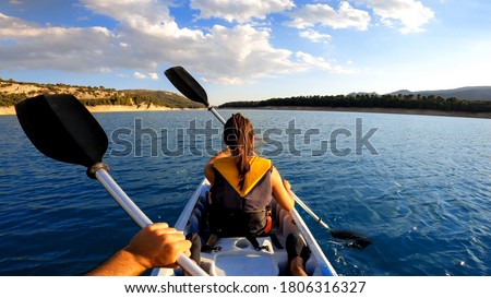Kayakers rowing at lake. Pov of woman kayaking in beautiful landscape at Embalse de la Bolera, Spain. Aquatic sports in kayak during summer concept.