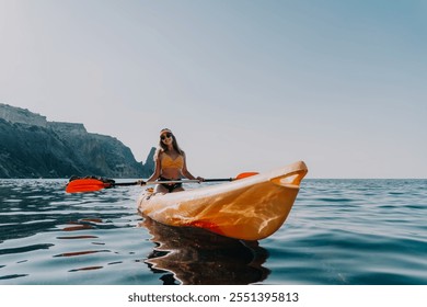 Kayaking, Ocean, Adventure: Woman Paddling Kayak on Calm Water with Rocky Cliffs in Background. - Powered by Shutterstock