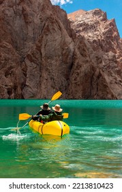 Kayaking on a mountain lake. Two men are sailing on a red canoe along the lake along the rocks. The theme of water sports and summer holidays. - Shutterstock ID 2213810423