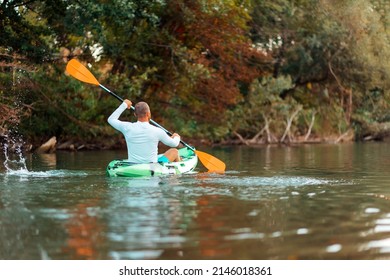 Kayaking On The River. Adult Man Floating At The Kayak. Back View. Copy Space. The Concept Of The World Tourism Day.