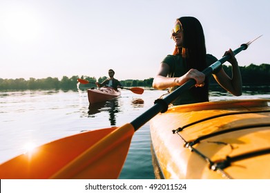 Kayaking together. Beautiful young couple kayaking on lake together and smiling  - Powered by Shutterstock