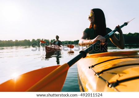 Kayaking together. Beautiful young couple kayaking on lake together and smiling 