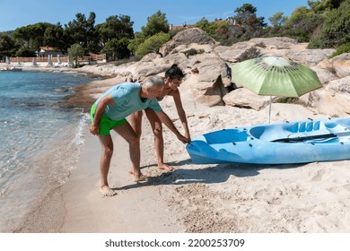 Kayaking.Happy Mature  Couple Pulling Out Kayak To The Sea. Leisure Activities On The Sea.