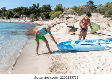 Kayaking.Happy Mature  Couple Pulling Out Kayak To The Sea. Leisure Activities On The Sea.