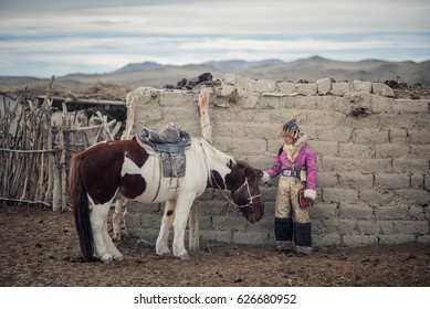 Kazakh Girl Eagle Hunters In Traditionally Wearing Typical Mongolian Dress Culture Of Mongolia She Rider Horse On Altai Mountain Background At Ba-yan UlGII, MONGOLIA