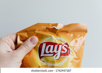 KAZAN, REPUBLIC OF TATARSTAN / RUSSIA - MAY 24 2020: Hand Holding A Pack Of Crisps Lays With Cheese On A White Background. Lays Is One Of The Most Famous Brands Of Chips In The World