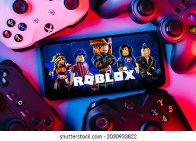 Kazan, Russia - August 25, 2021: Roblox is an online game platform and game creation system. A smartphone with the Roblox logo on the screen surrounded by gamepads.