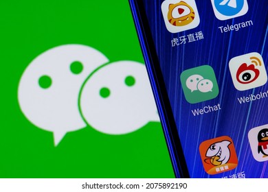 Kazan, Russia - Nov 16, 2021: The icon of the WeChat messenger application among other applications on the smartphone screen. On the background is the WeChat logo.