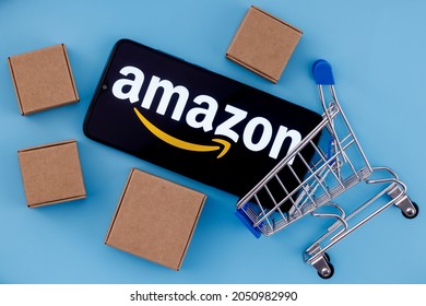 Kazan, Russia - Oct 02, 2021: Amazon is an American company, one of the world's largest e-commerce platform markets. Smartphone with Amazon logo on the screen, shopping cart and parcels.
