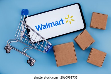 Kazan, Russia - Oct 20, 2021: Walmart is an American multinational retail corporation. Smartphone with Walmart logo on the screen, shopping cart and parcels.