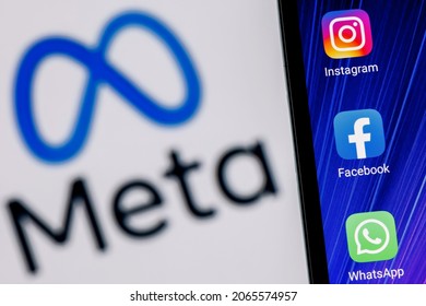Kazan, Russia - Oct 28, 2021: Facebook changes its name to Meta. Smartphone with Facebook, Whatsapp and Instagram app icon on the background of Meta logo.