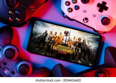 Kazan, Russia - September 01, 2021: PlayerUnknown Battlegrounds (PUBG) is an online multiplayer battle royale game. A smartphone with the frame from PUBG Mobile on the screen surrounded by gamepads.
