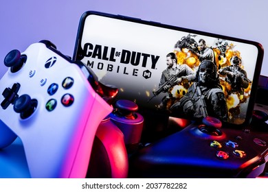 Kazan, Russia - September 07, 2021: Call Of Duty: Mobile Is A Free-to-play Shooter Game. A Smartphone With The Frame From Call Of Duty On The Pile Of The Gamepads.