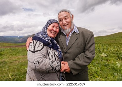 KAZARMAN, KYRGYZSTAN - June 2009: Old Muslim Couple Affectionately Holding Each Other In A Pasture, Called Jailoo