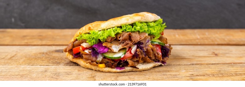 Döner Kebab Doner Kebap fast food in flatbread on a wooden board panorama snack