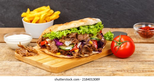 Döner Kebab Doner Kebap fast food meal in flatbread with fries on a wooden board panorama board