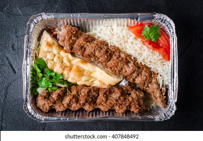 Kebab with rice and flatbread in box on dark background. Selective focus