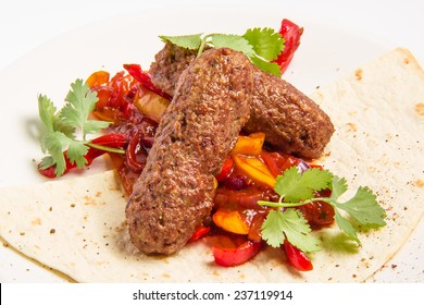 kebab and vegetables in sauce on a background of cakes