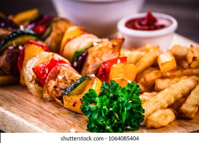 Kebabs - gegrilltes Fleisch mit Pommes frites und Gemüse auf Holzhintergrund