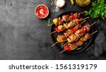 Kebabs - grilled meat skewers, shish kebab with vegetables on black wooden background.	
