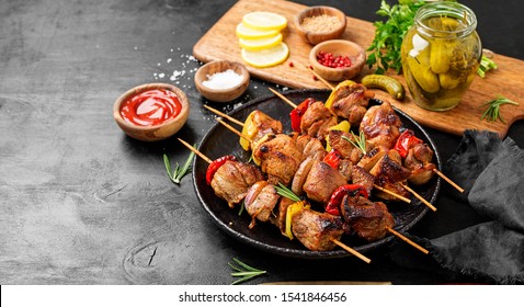 Kebabs - grilled meat skewers, shish kebab with vegetables on black wooden background.