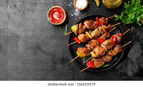 Kebabs - grilled meat skewers, shish kebab with vegetables on black wooden background.	
					