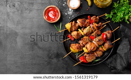 Kebabs - grilled meat skewers, shish kebab with vegetables on black wooden background.	
