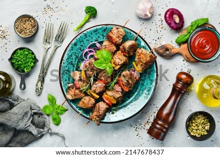 Kebabs - grilled meat skewers, shish kebab with vegetables on a plate. On a concrete old table. Top view.