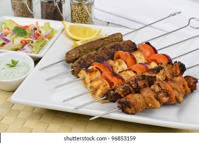 Kebabs - Selection of chicken tikka, paneer tikka and seekh kebabs served with crunchy salad, mint raita and lemon wedges.